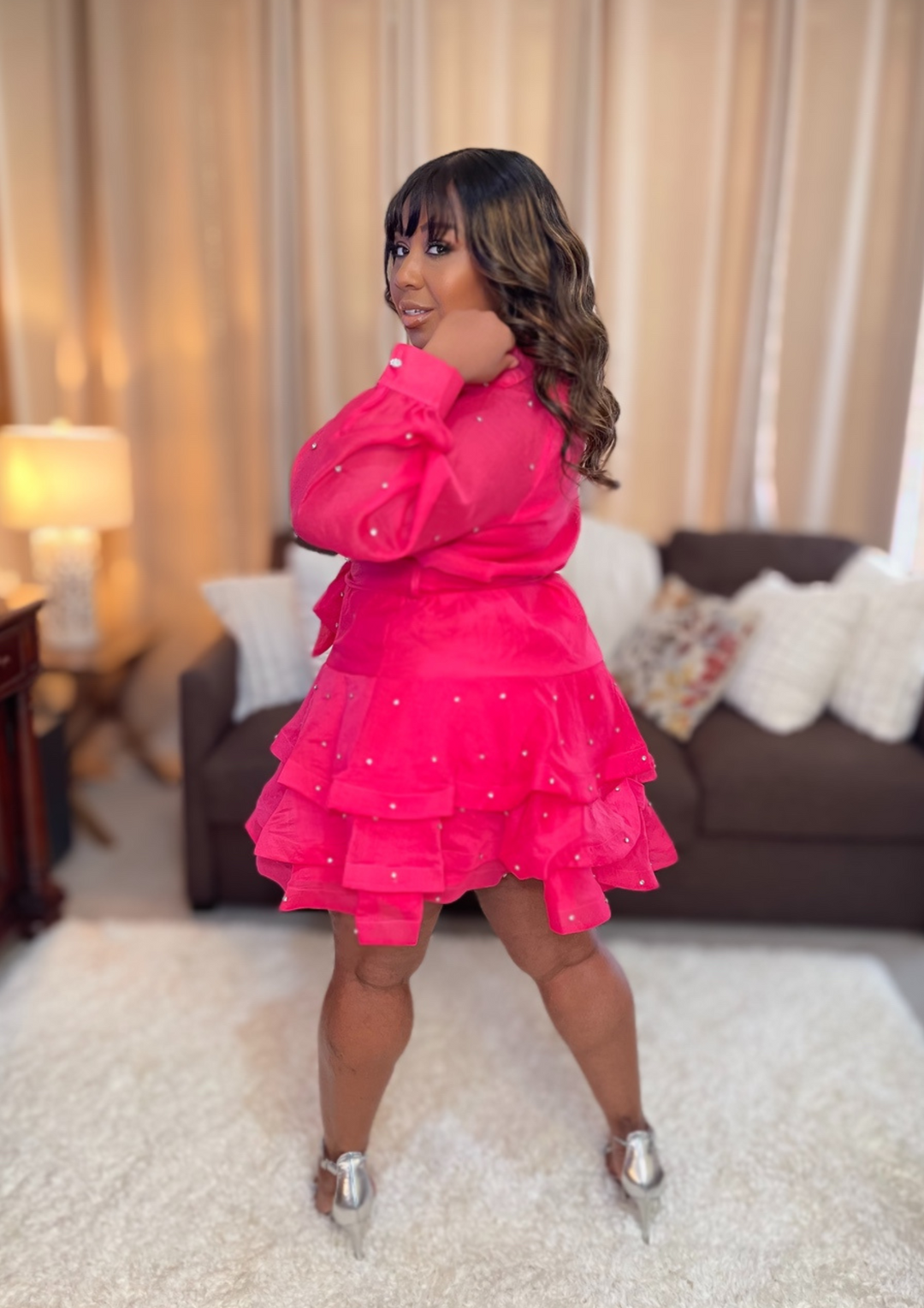 Woman in a bright pink dress standing in a living room.