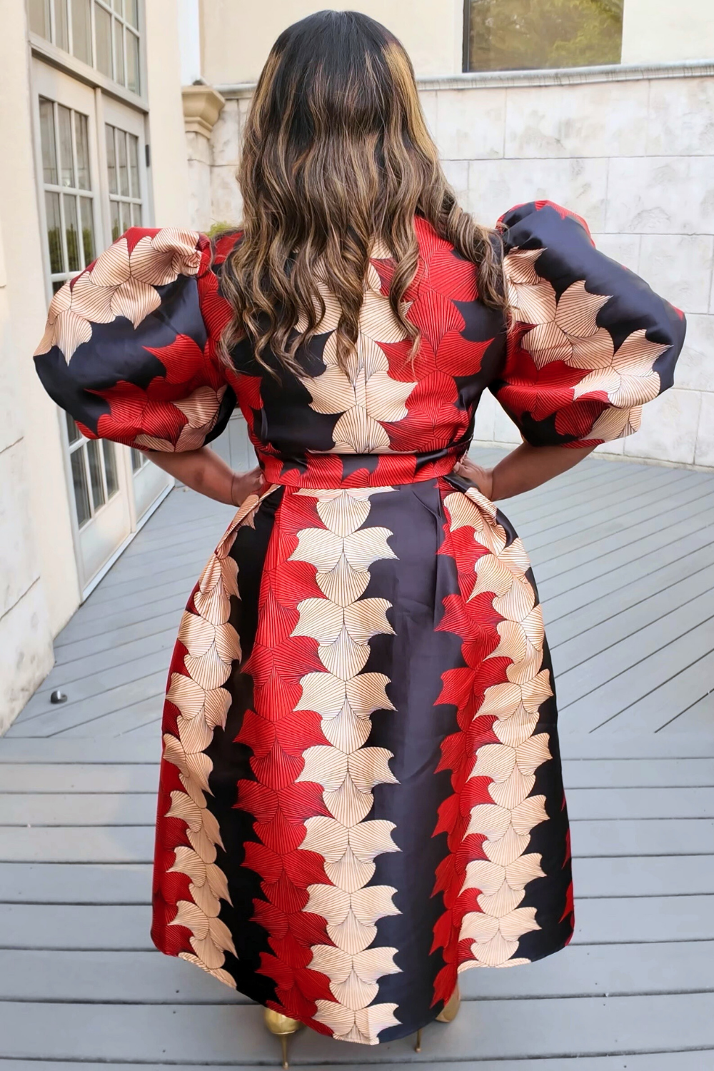 Woman wearing a colorful dress with a patterned design outdoors.