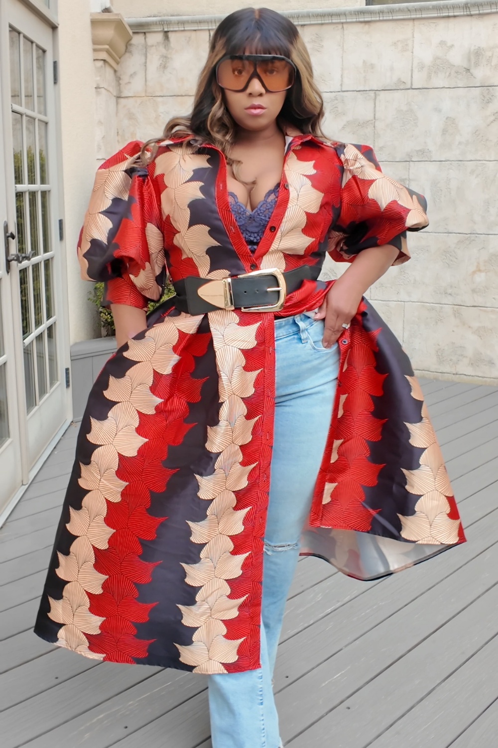 Woman wearing a patterned dress with a belt, standing on a Terrace.
